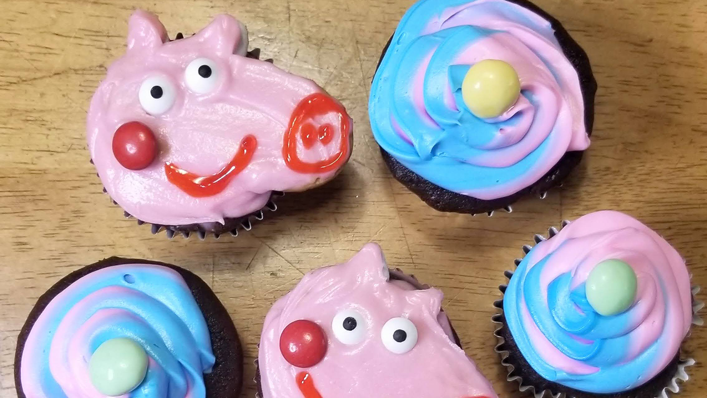 peppa pig-inspired cupcakes next to pink and blue swirl cupcakes